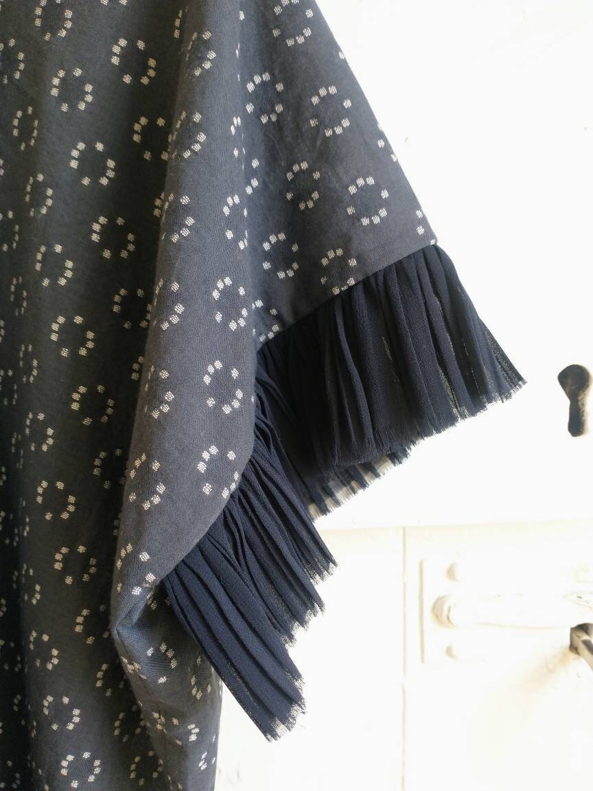 The sleeve trim is made from a slightly sheer navy blue chiffon. The edge is evenly and delicately fayed. The chiffon has been pleated into fine irregular pleats. The chiffon trim is about 2 inches long.