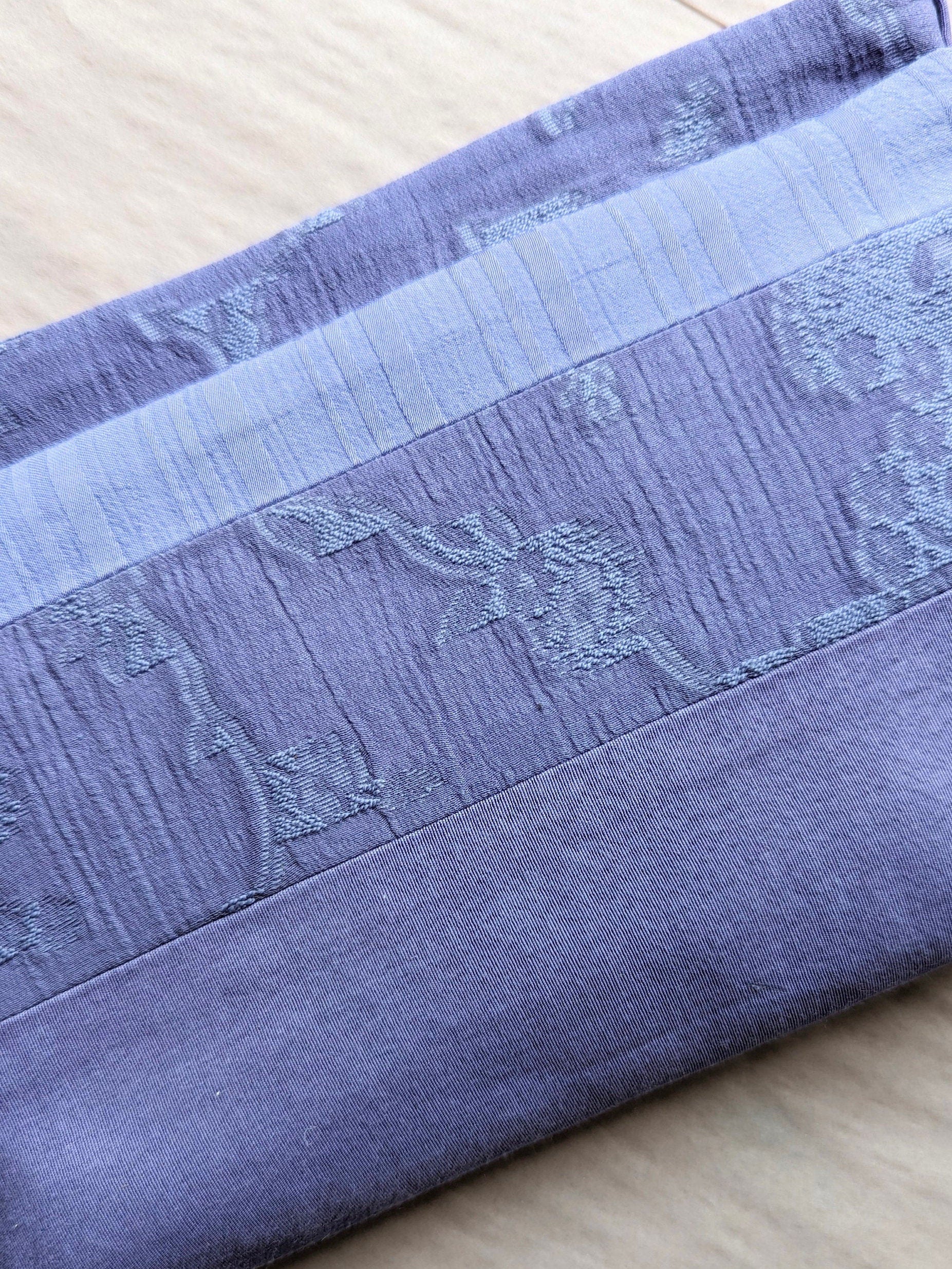 Close up picture showing the detail of the fabrics. Each has a different texture. One has a floral pattern woven into into, one is smooth with a twill weave and one, a slightly lighter shade, has unequal stripes woven in running vertically.