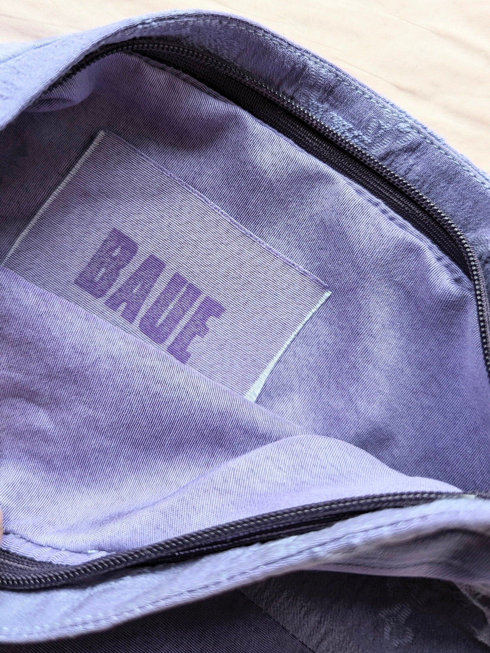 Close up image of the brand label. It is attached to the lining of the makeup bag, on the inside. The label reads B A U E which is pronounced bower. The label is made from a rectangle of the silk fabric you can see on the outside of the makeup bag